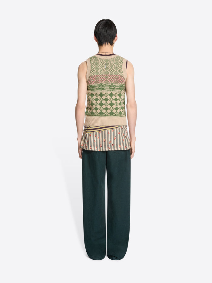 Back view of a person wearing a patterned sleeveless top and dark pants on a white background