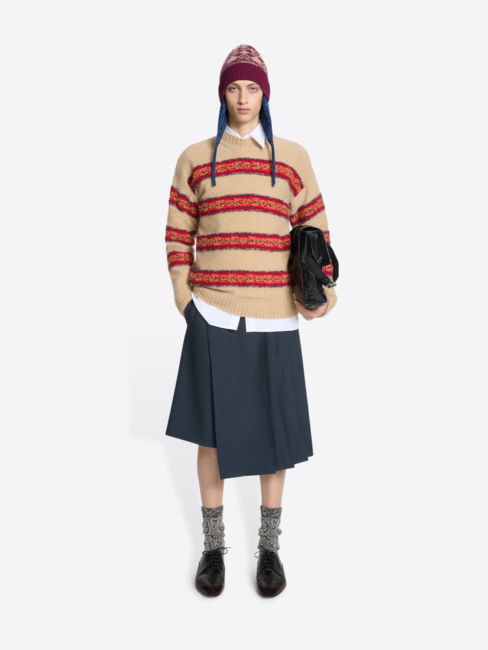 Person wearing a striped sweater, skirt, and patterned hat on a white background