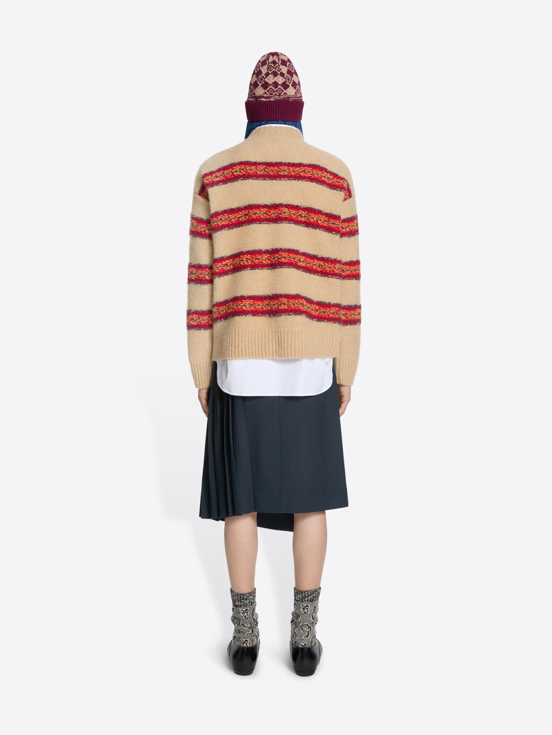 Back view of a person wearing a striped sweater, skirt, and patterned hat on a white background