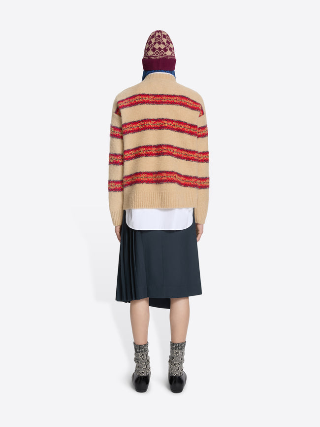 Back view of a person wearing a striped sweater, skirt, and patterned hat on a white background