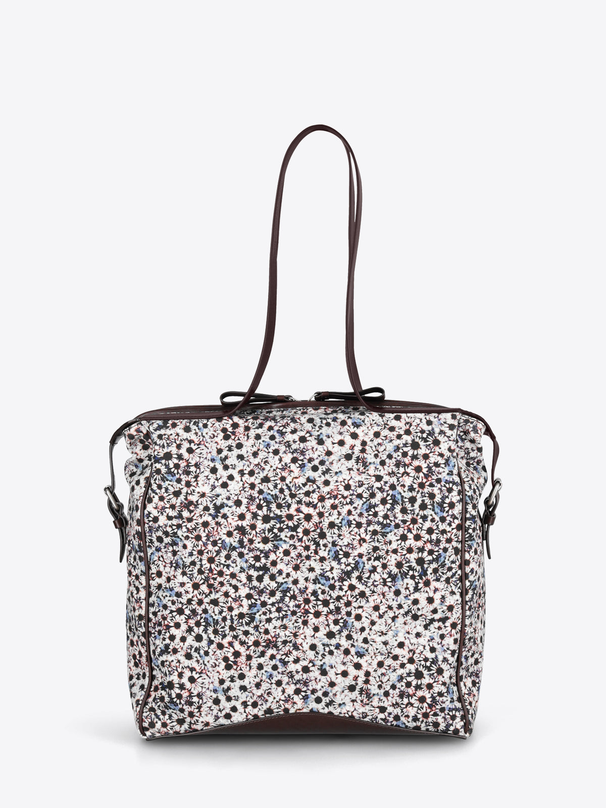 A structured tote bag with a dense multicolor floral print pattern on a white base, featuring dark brown leather trim and shoulder straps.