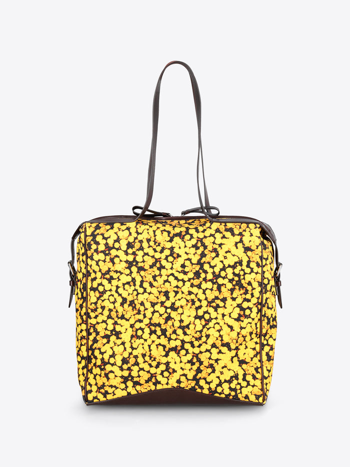 A square-shaped shoulder bag with a bright yellow and black floral patterned body, featuring dark brown leather trim and a single shoulder strap, shown against a plain light gray background.