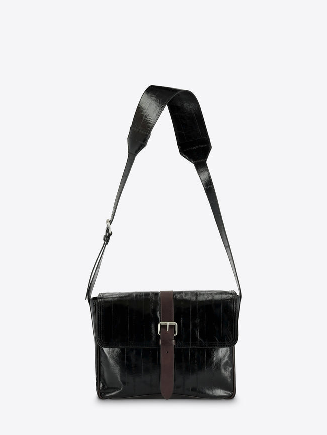 A black leather messenger bag with a brown leather strap detail and silver buckle, featuring a wide adjustable shoulder strap, shown against a light gray background.