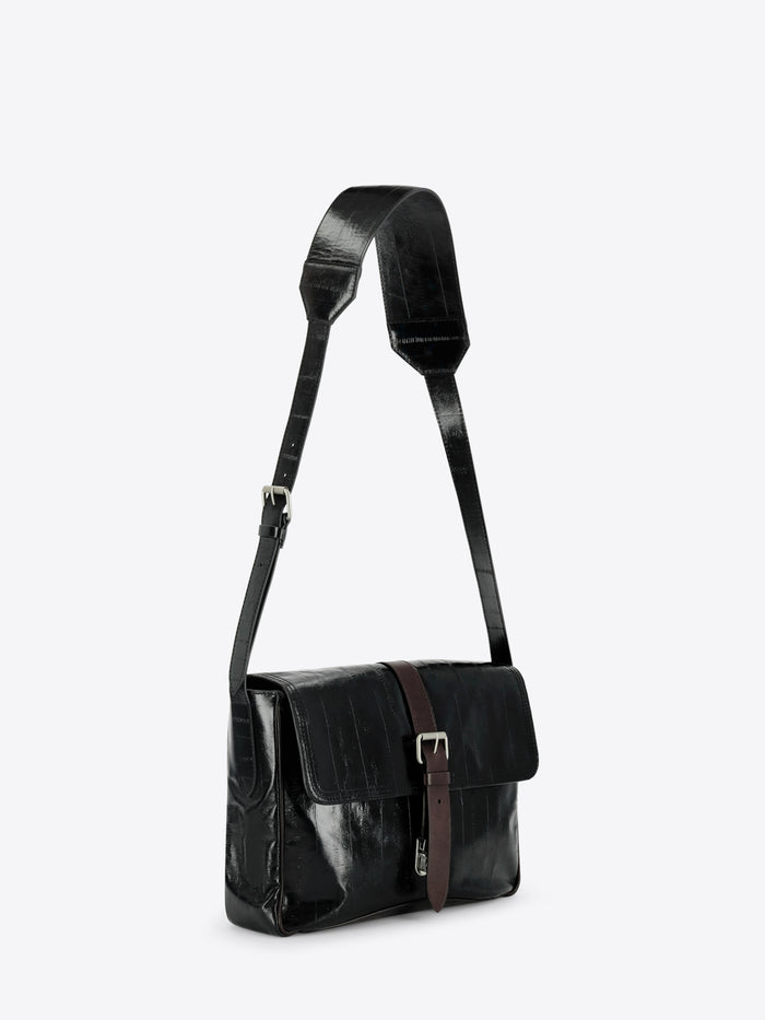 A black leather shoulder bag with a glossy finish, featuring a brown leather strap detail and silver buckle on the front flap, set against a light gray background.