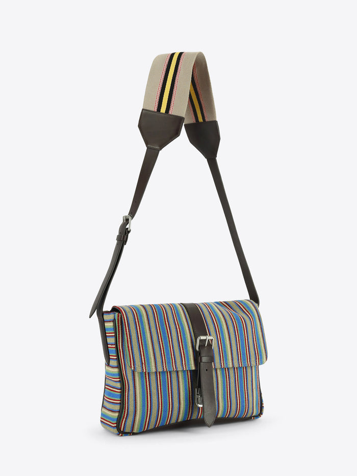 Multicolored striped shoulder bag with dark brown leather trim, a front buckle closure and an adjustable striped strap, shown against a light grey background.