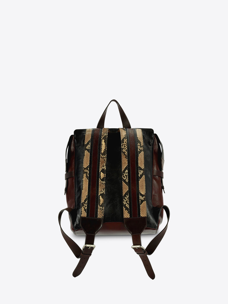 A structured leather backpack with dark brown leather and vertical beige and black snakeskin patterned stripes, shown from the back against a light gray background.