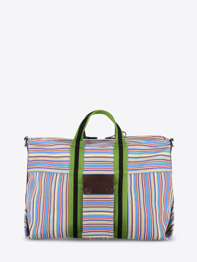 A striped bag with multicolor vertical stripes in blue, red, yellow, and white, featuring green handles and green side trim, set against a light gray background.
