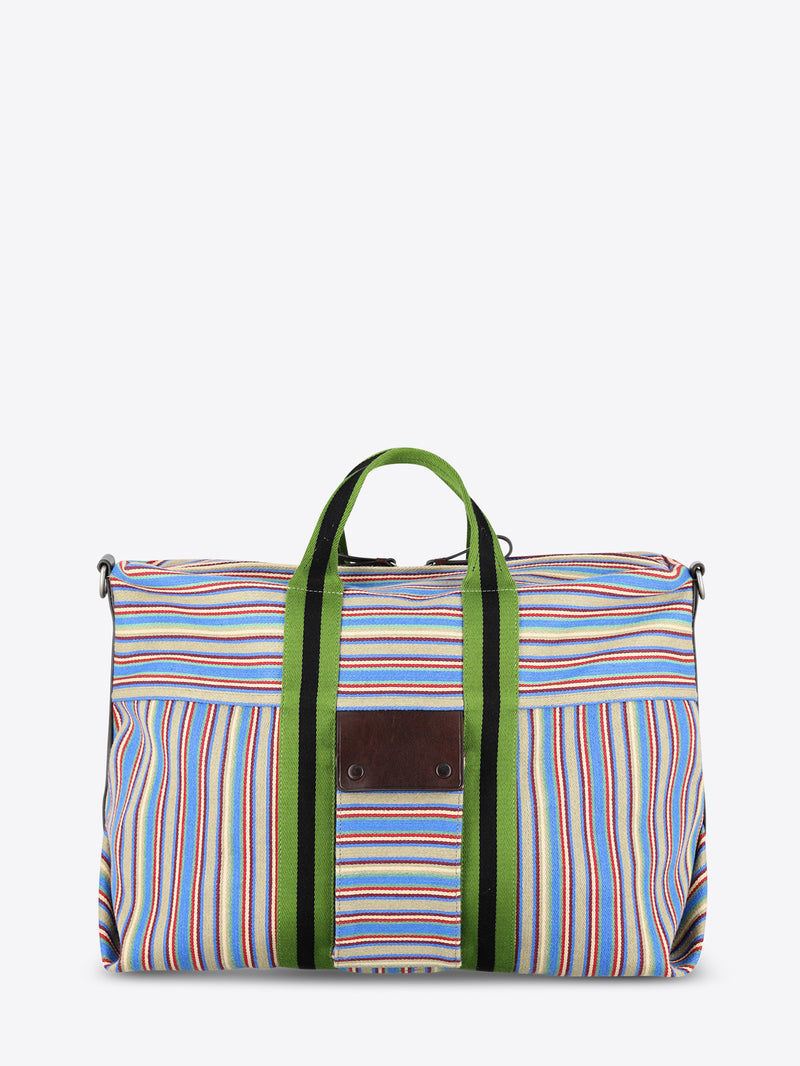 A striped bag with multicolor vertical stripes in blue, red, yellow, and white, featuring green handles and green side trim, set against a light gray background.