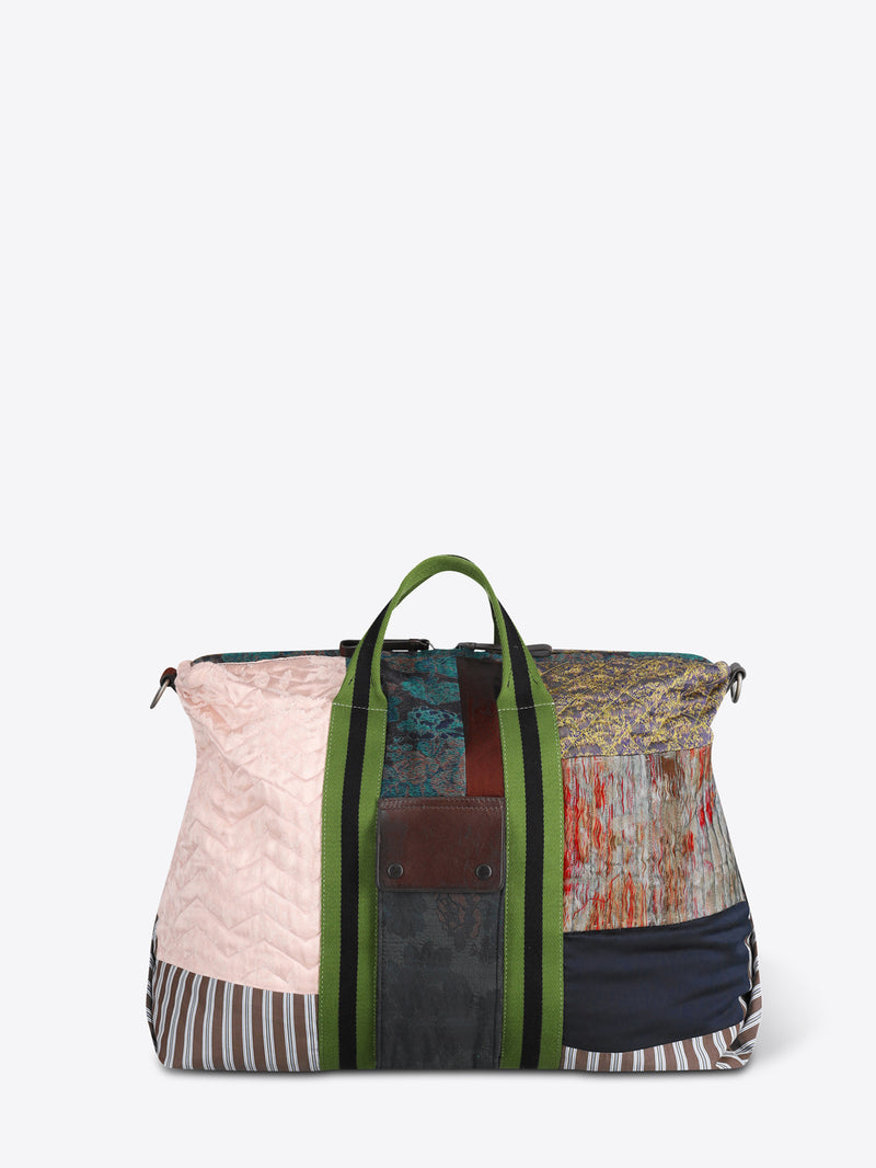 A patchwork duffel bag with a light pink quilted panel, striped fabric, a green zipper, and a black shoulder strap, shown on a light gray background.