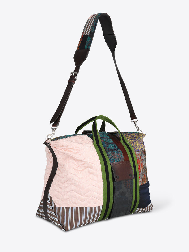 A patchwork duffel bag with a light pink quilted panel, striped fabric, a green zipper, and a black shoulder strap, shown on a light gray background.