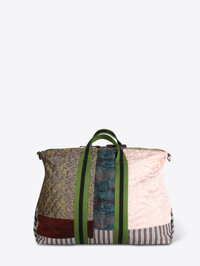 A patchwork duffel bag with a light pink quilted panel, striped fabric, a green zipper, and a black shoulder strap, shown on a light gray background.