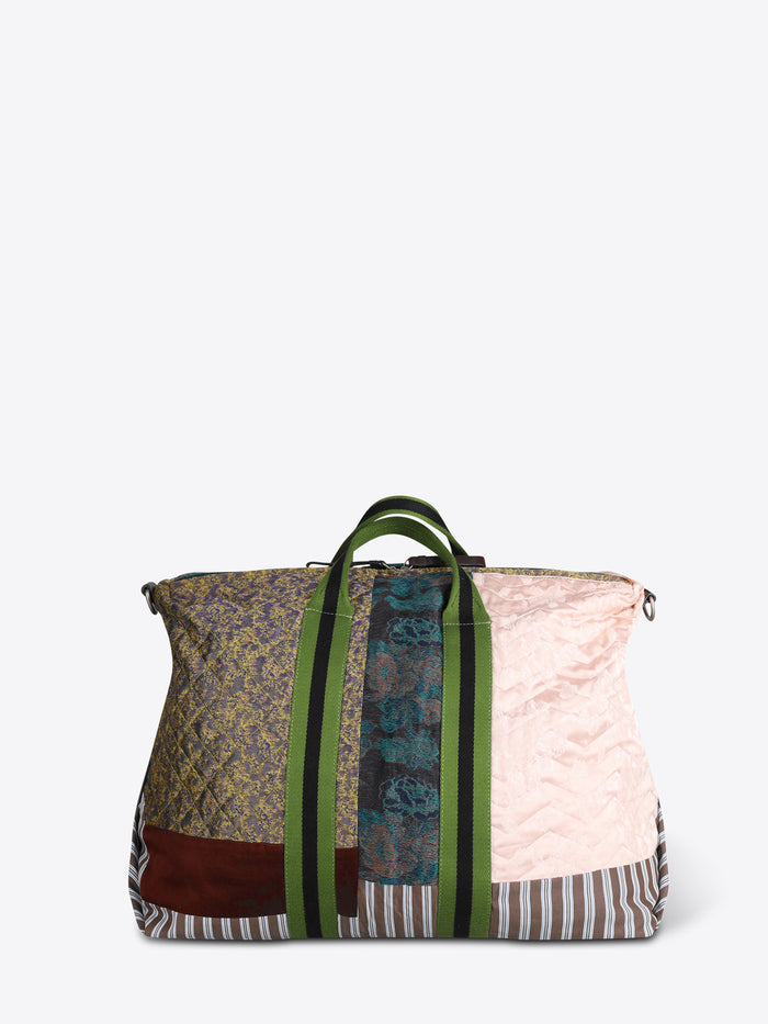 A patchwork duffel bag with a light pink quilted panel, striped fabric, a green zipper, and a black shoulder strap, shown on a light gray background.