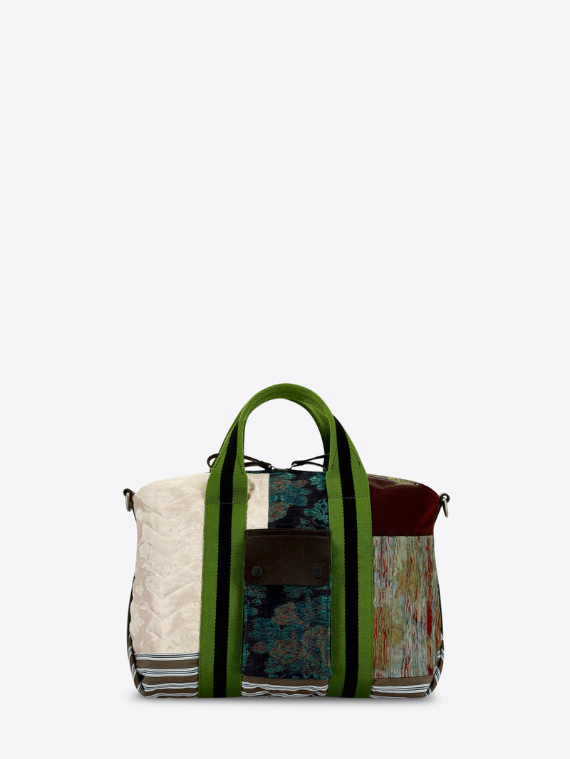 A patchwork tote bag featuring a mix of textures and prints, set against a light gray background.