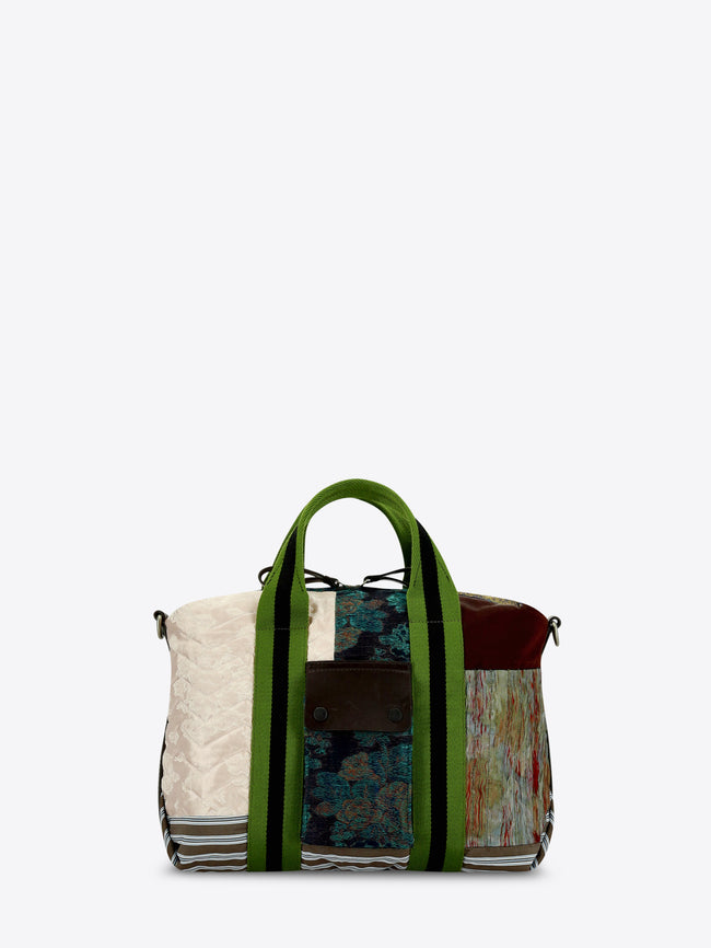 A patchwork tote bag featuring a mix of textures and prints, set against a light gray background.
