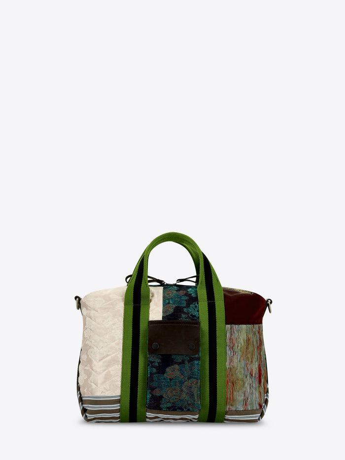 A patchwork tote bag featuring a mix of textures and prints, set against a light gray background.