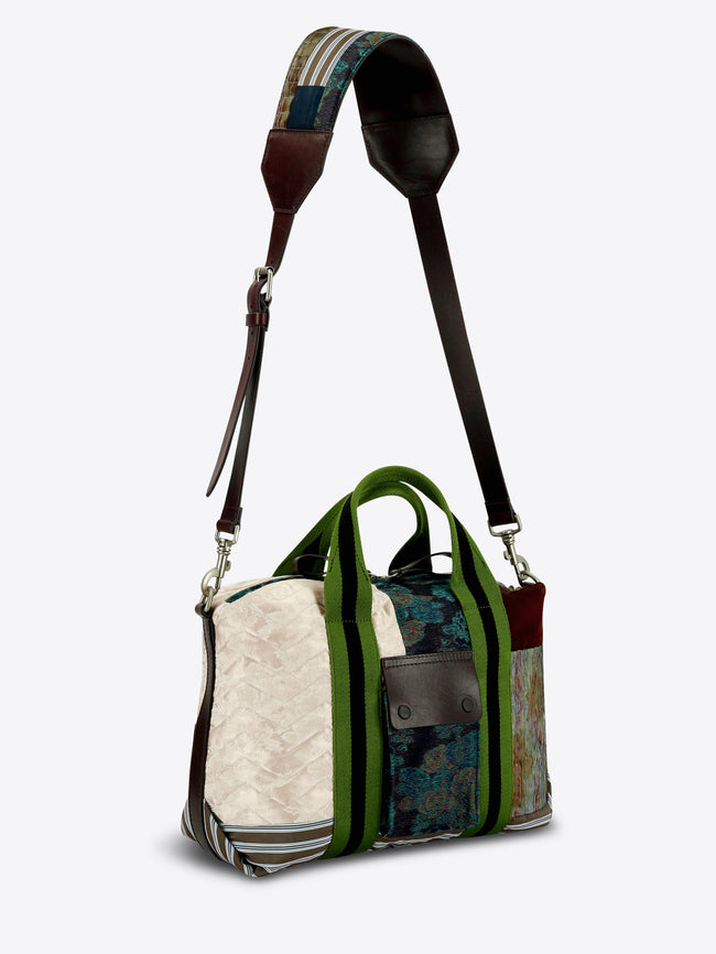 A patchwork tote bag featuring a mix of textures and prints, set against a light gray background.