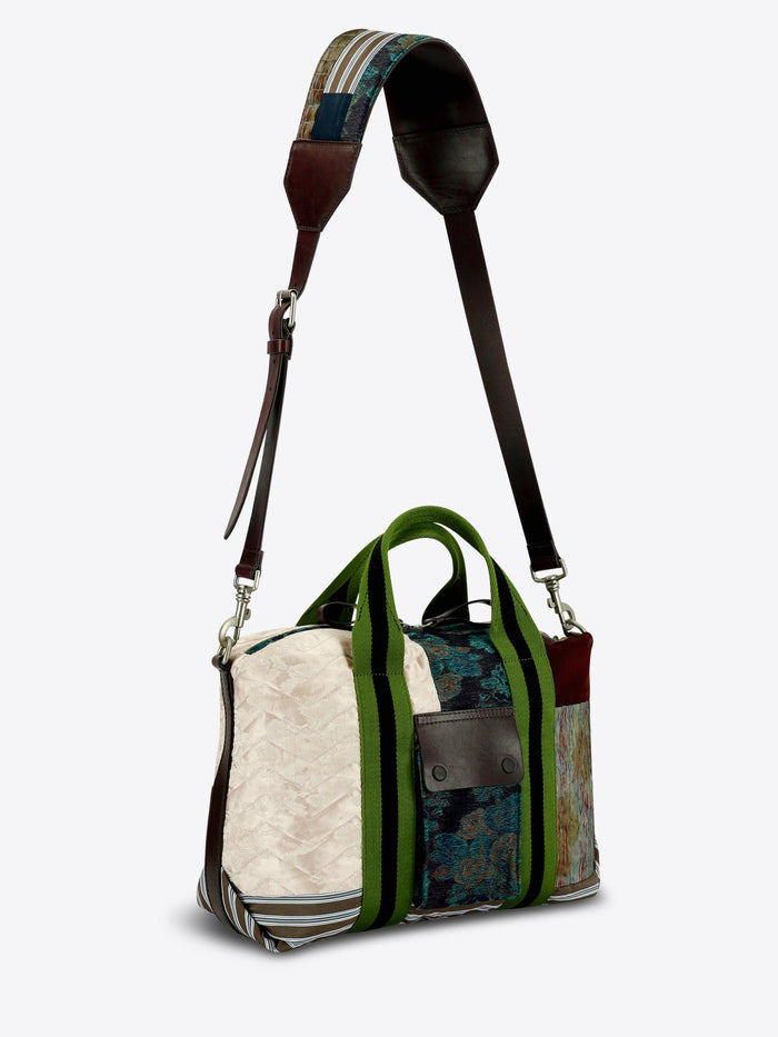 A patchwork tote bag featuring a mix of textures and prints, set against a light gray background.
