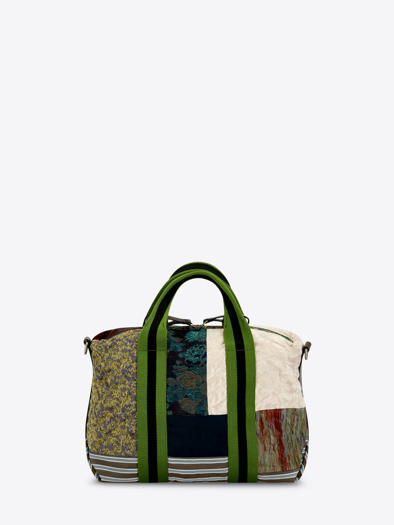 A patchwork tote bag featuring a mix of textures and prints, set against a light gray background.
