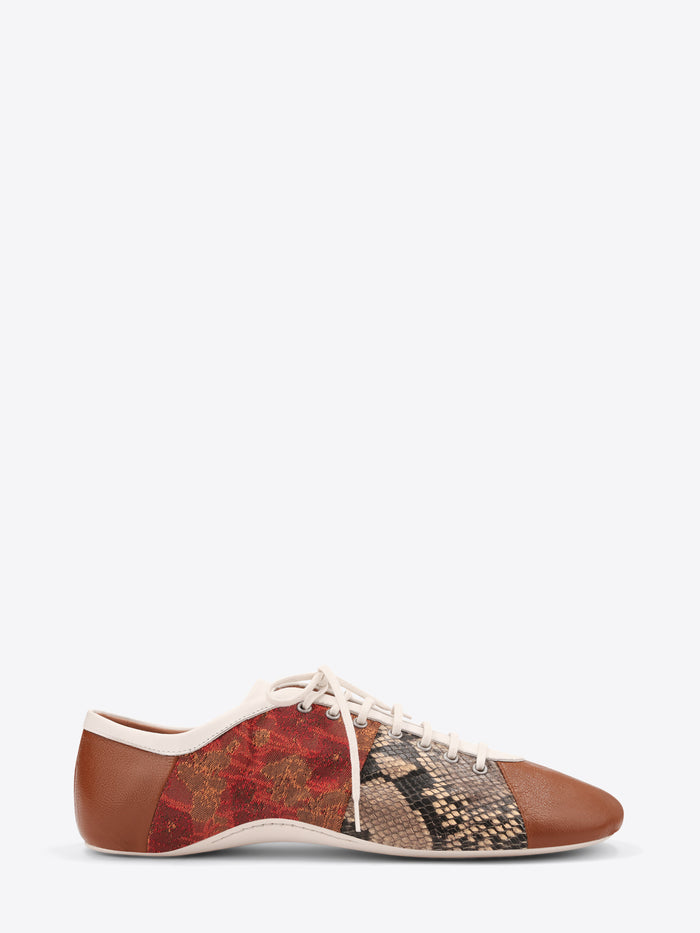 A low-top lace-up shoe featuring a brown leather toe and heel, a red and gold patterned side panel, and a snakeskin-patterned panel on the front, set against a light gray background.