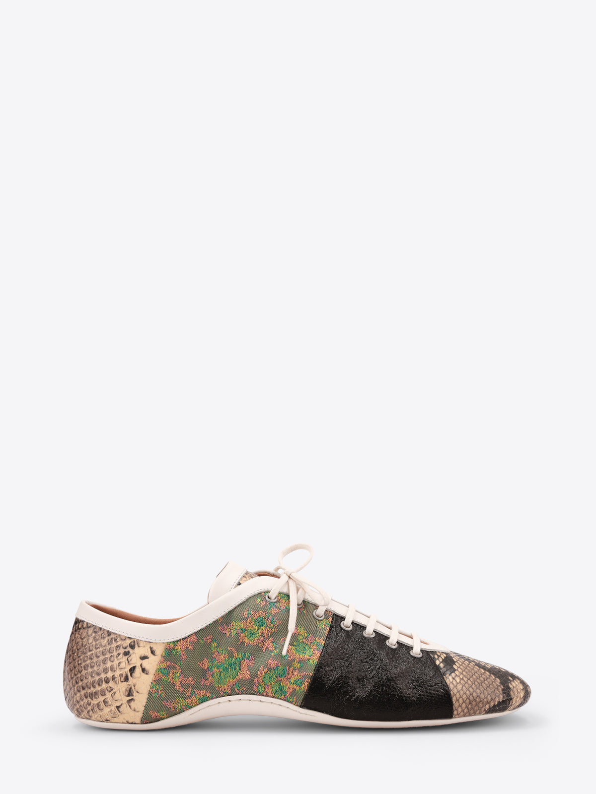 A low-top sneaker featuring mixed animal print panels, including a beige snakeskin pattern, a green and brown floral section, a black textured panel, and a beige snakeskin pattern on the toe with white laces on a light gray background.