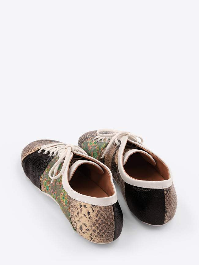 A pair of low-top sneakers featuring mixed animal print panels, including a beige snakeskin pattern, a green and brown floral section, a black textured panel, and a beige snakeskin pattern on the toe with white laces on a light gray background.