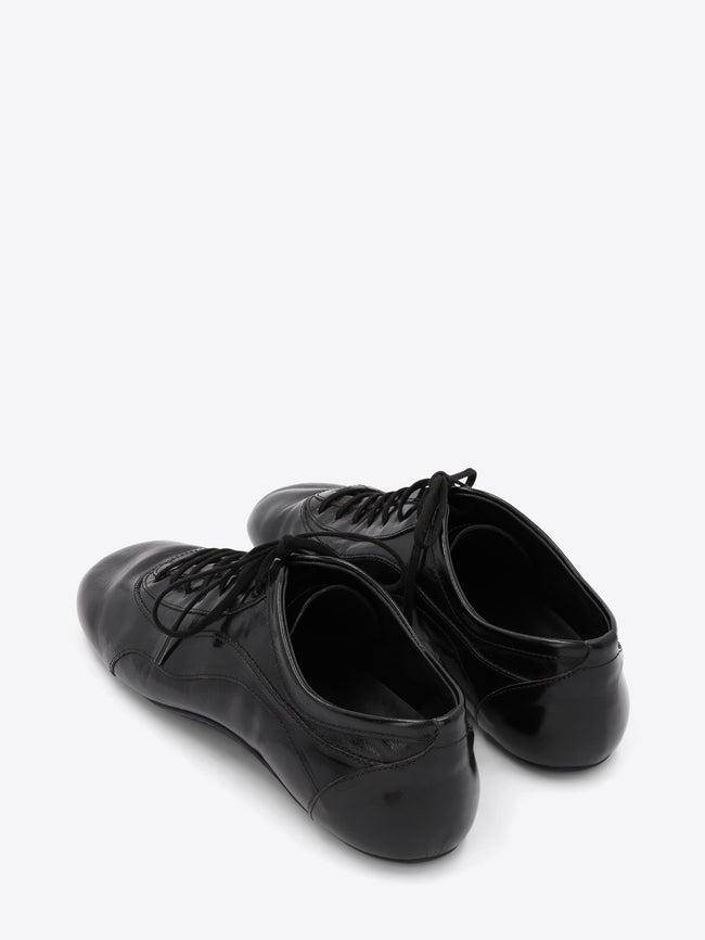 A pair of black leather low-top lace-up shoes with a glossy finish, displayed on a light gray background.