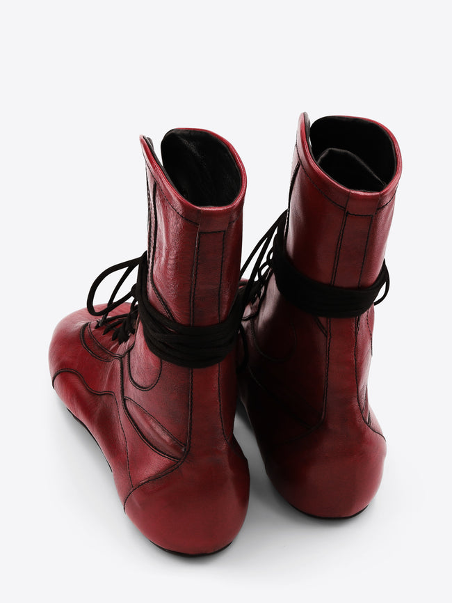 A pair of red leather lace-up boots with black laces, shown on a light gray background.