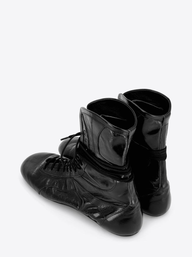 A pair of black leather lace-up boots with a glossy finish, shown on a light gray background.