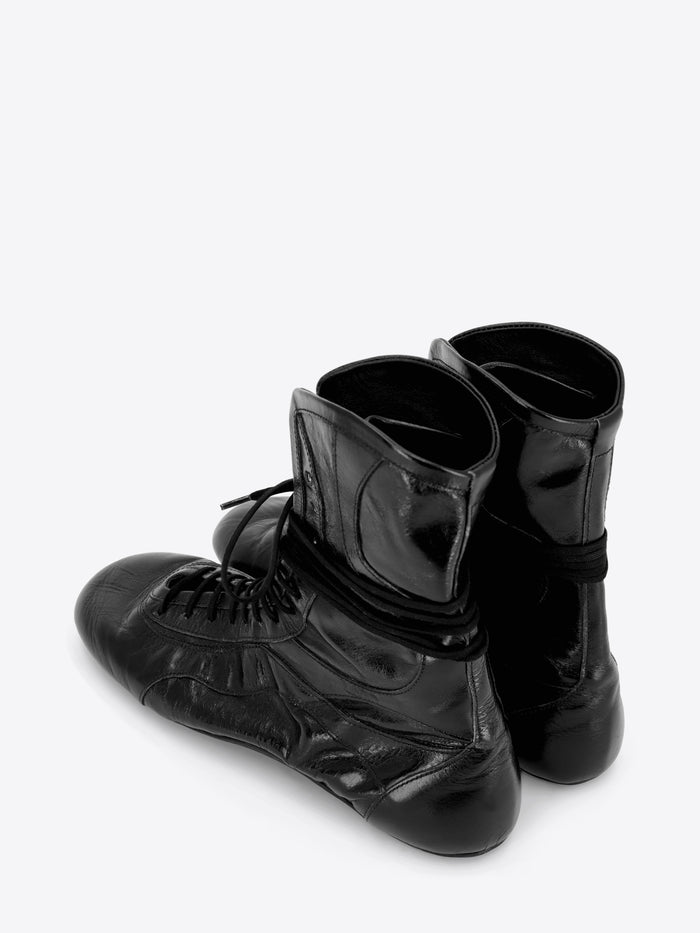A pair of black leather lace-up boots with a glossy finish, shown on a light gray background.