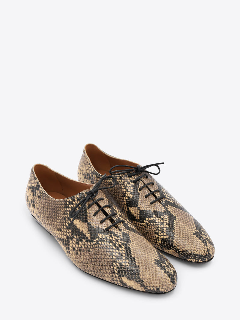 A pair of lace-up oxford shoes featuring a snakeskin pattern with black laces, shown on a light gray background.