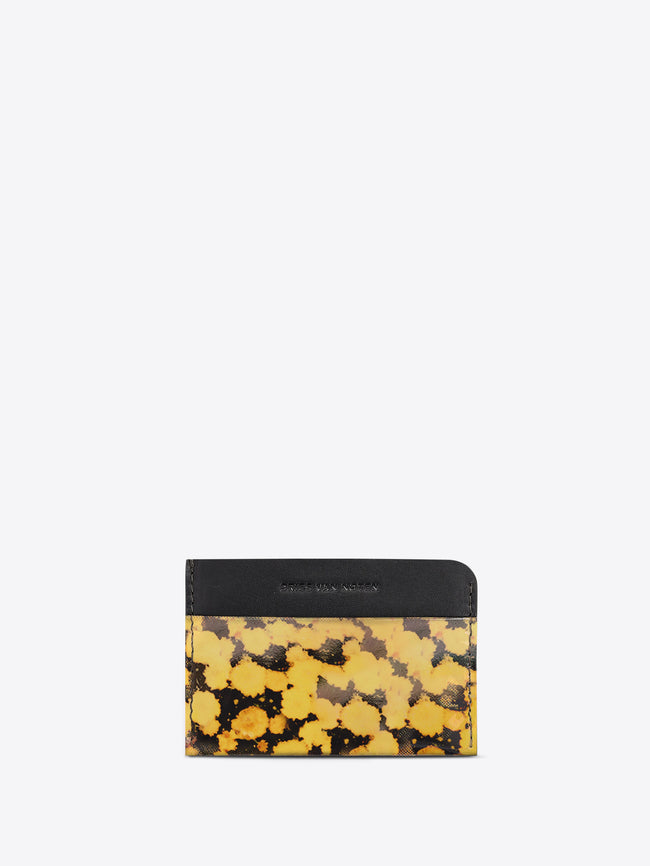 A card holder wallet, featuring a black leather top band with the brand name and a yellow and black abstract patterned lower section, set against a light gray background.