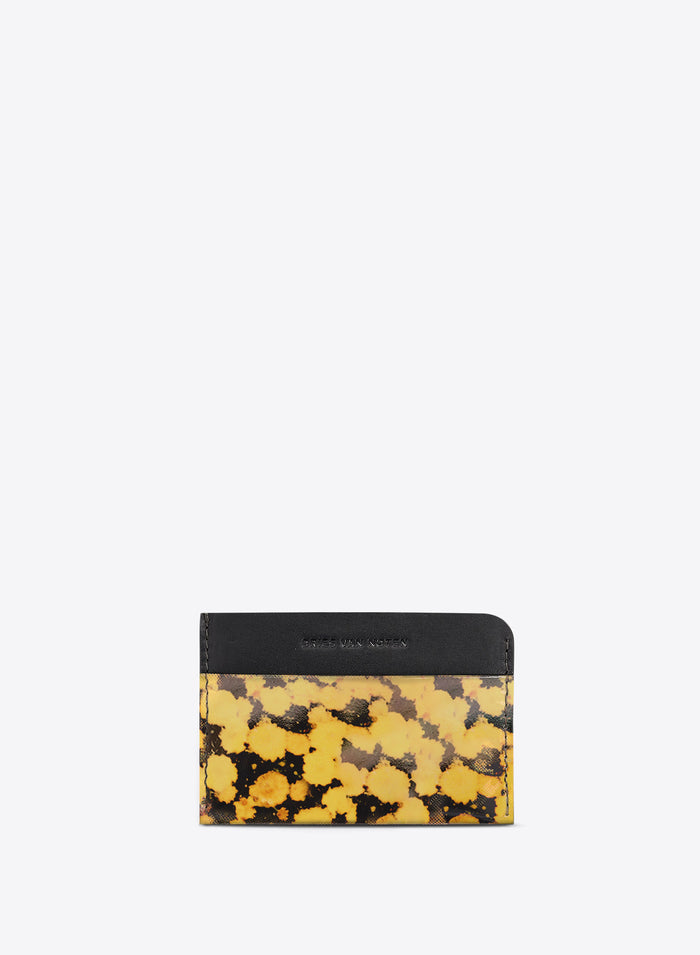 A card holder wallet, featuring a black leather top band with the brand name and a yellow and black abstract patterned lower section, set against a light gray background.