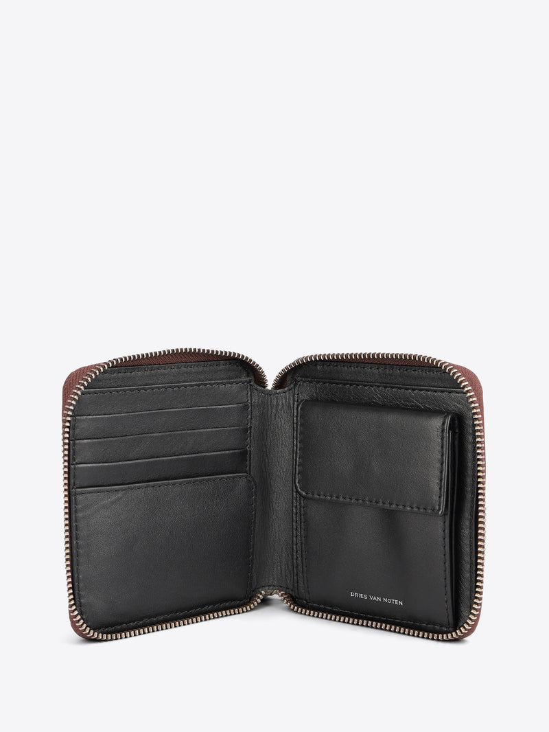 An open leather zip-around wallet with multiple card slots and a cardholder pocket, shown against a light gray background.