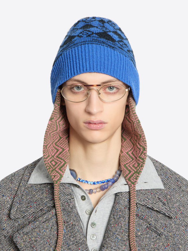 Person wearing a blue patterned knit hat on a white background