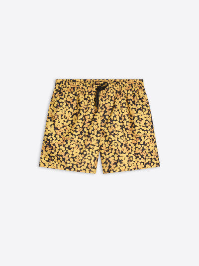 A pair of men's swim trunks featuring a dense yellow and black abstract floral, with a black drawstring at the elastic waistband, shown flat on a light gray background.
