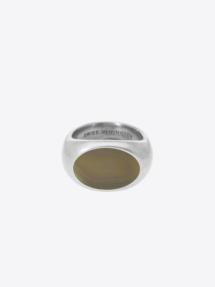 A silver signet ring with a polished oval face, featuring the engraved brand name 'DRIES VAN NOTEN' inside the band, set against a light gray background.
