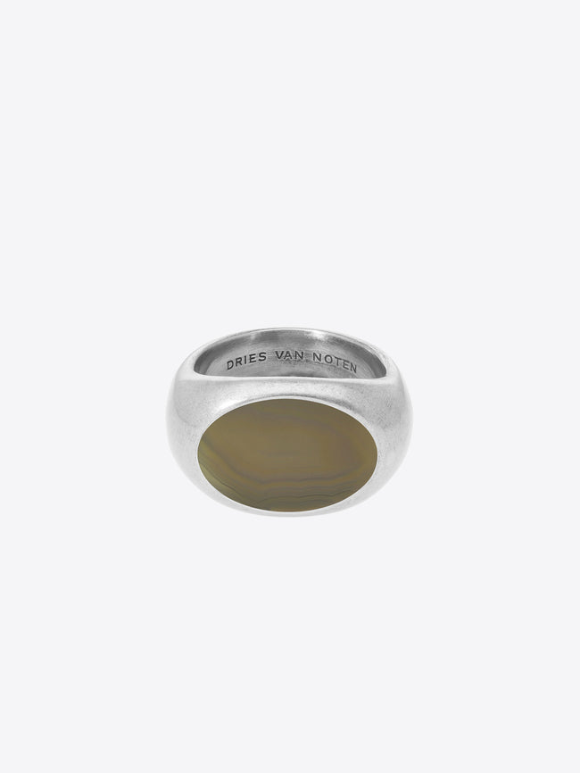 A silver signet ring with a polished oval face, featuring the engraved brand name 'DRIES VAN NOTEN' inside the band, set against a light gray background.