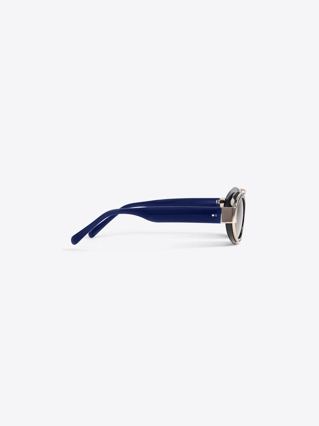 A pair of round-frame eyeglasses with dark blue acetate arms and silver metal rims, shown from a side profile on a light gray background.