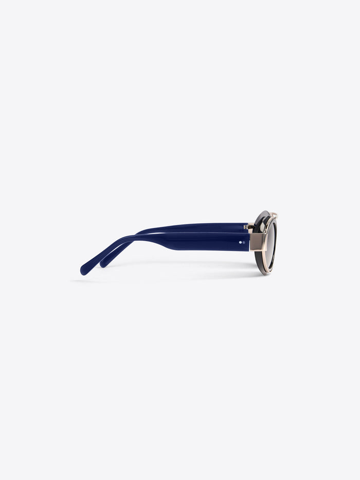 A pair of round-frame eyeglasses with dark blue acetate arms and silver metal rims, shown from a side profile on a light gray background.