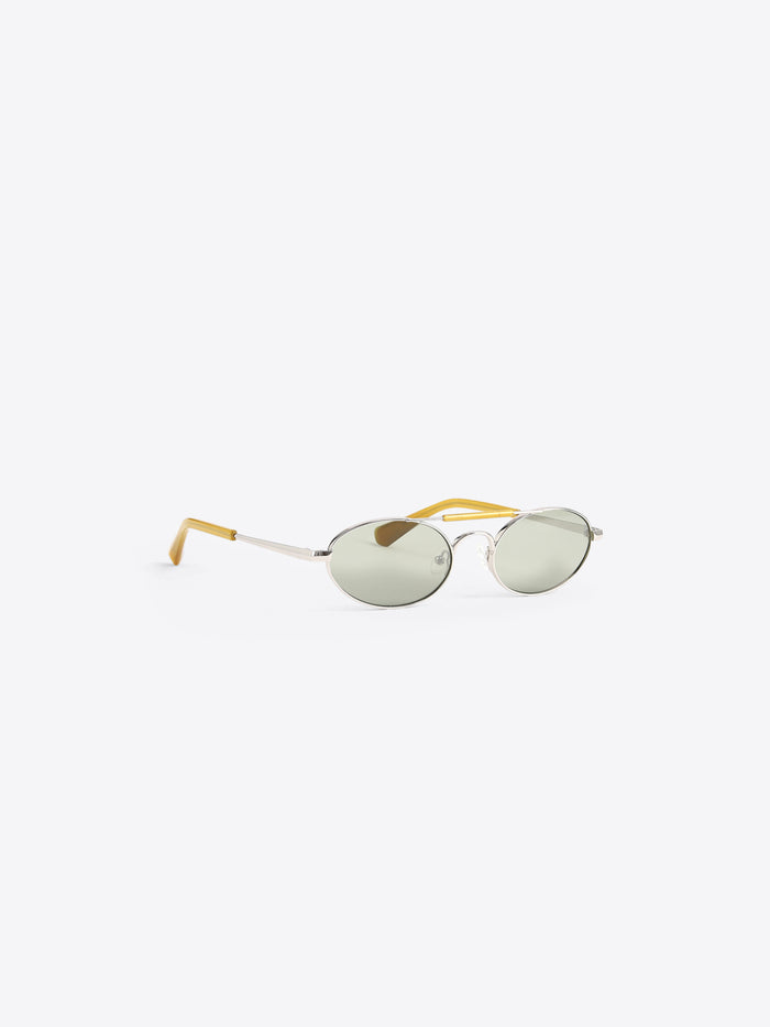 Oval sunglasses with light green tinted lenses, a silver metal frame, and yellow acetate temples, shown on a light gray background.