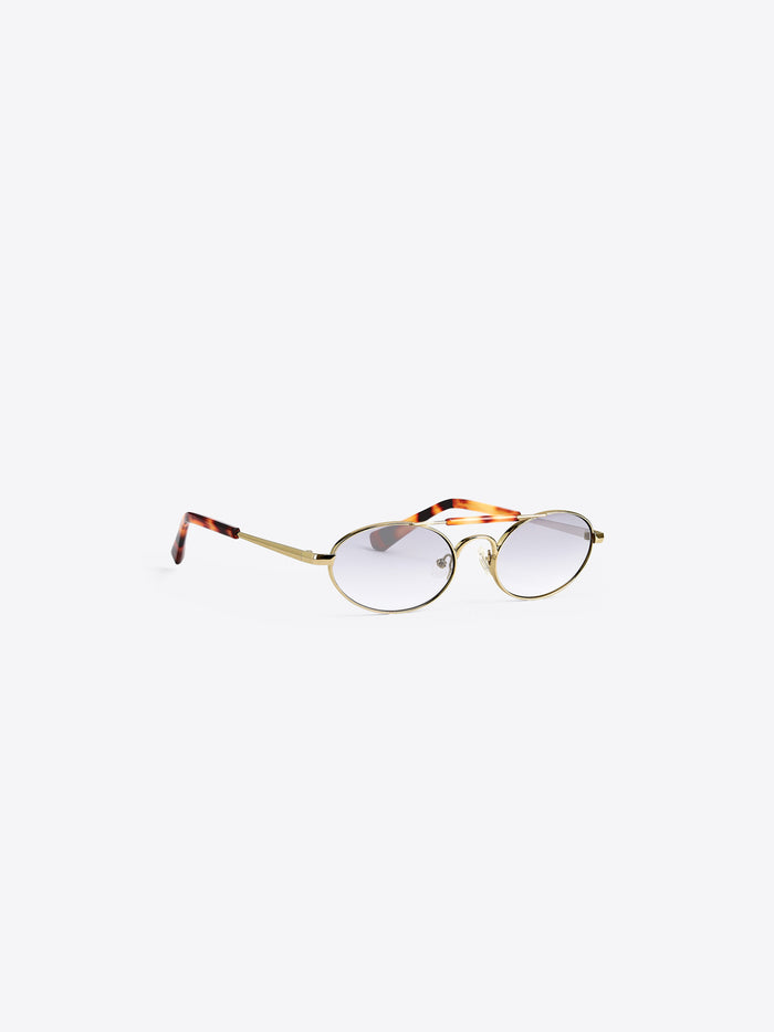 Oval eyeglasses with a gold metal frame, clear-to-light-tinted lenses, and tortoiseshell-patterned temples, shown on a light gray background.