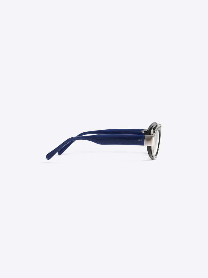 A round black-rimmed eyeglasses with dark blue acetate arms and a silver metal frame, shown from a side profile on a light gray background.