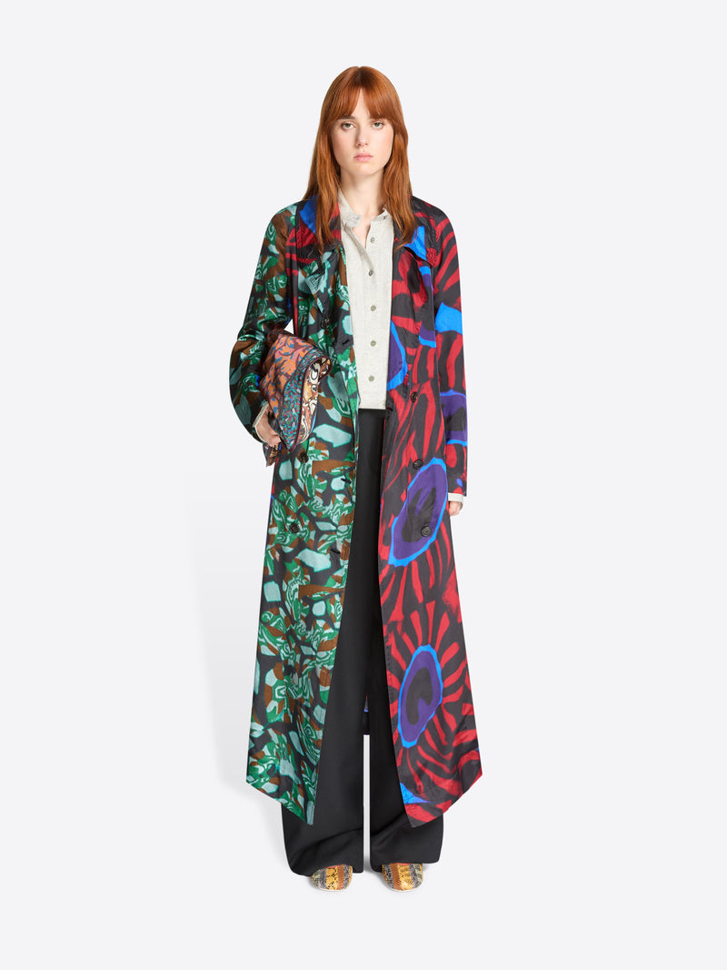 Woman wearing a long, colorful patterned coat on a white background