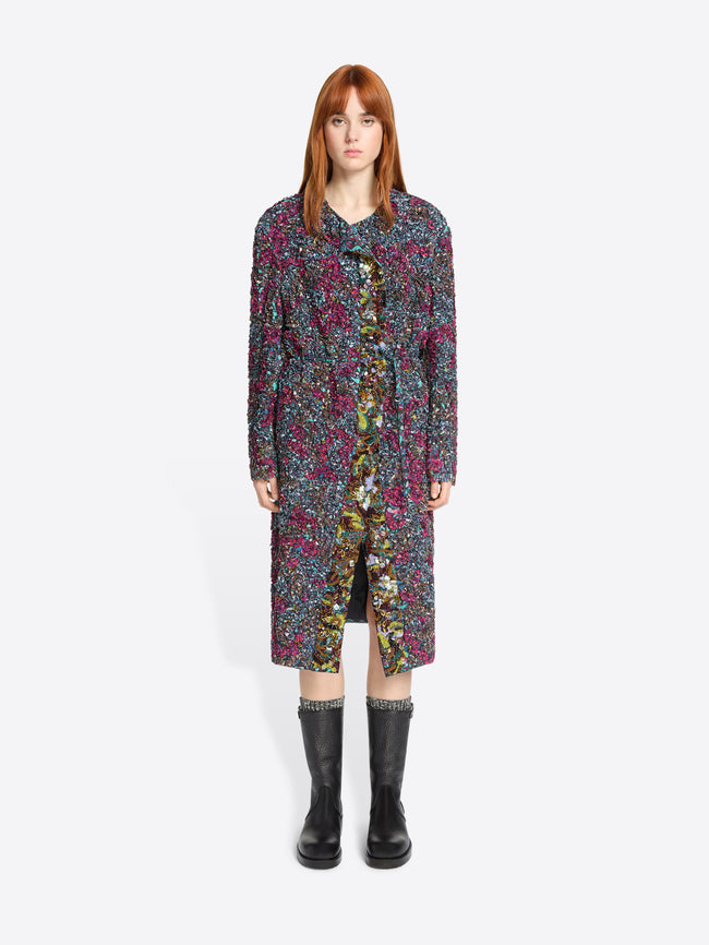 Woman wearing a long, patterned dress with black boots on a white background