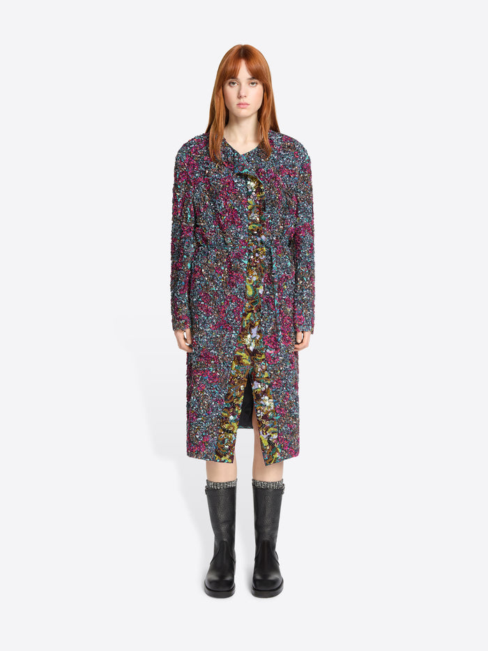 Woman wearing a long, patterned dress with black boots on a white background