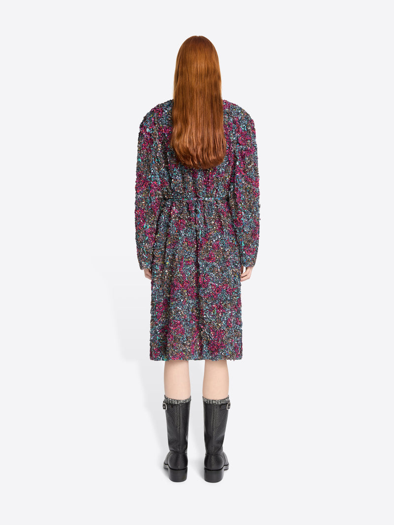 Back view of a person wearing a floral dress with black boots on a white background