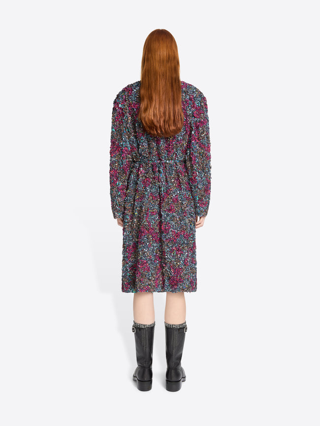 Back view of a person wearing a floral dress with black boots on a white background
