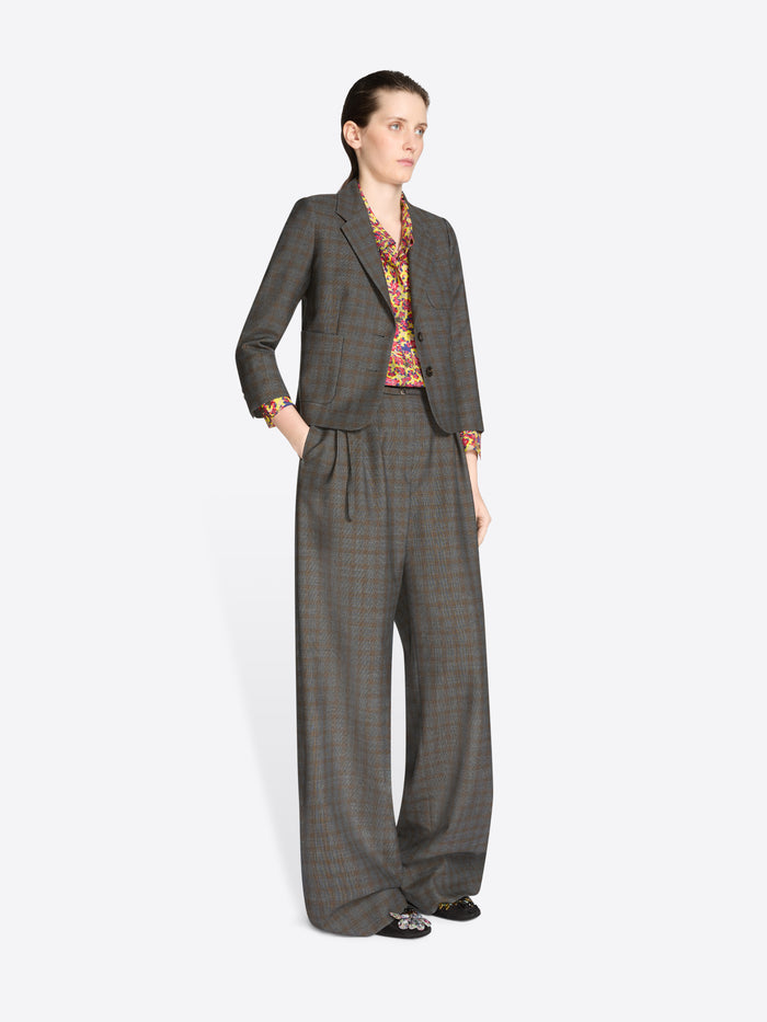 Woman wearing a gray checkered suit with a patterned blouse on a white background