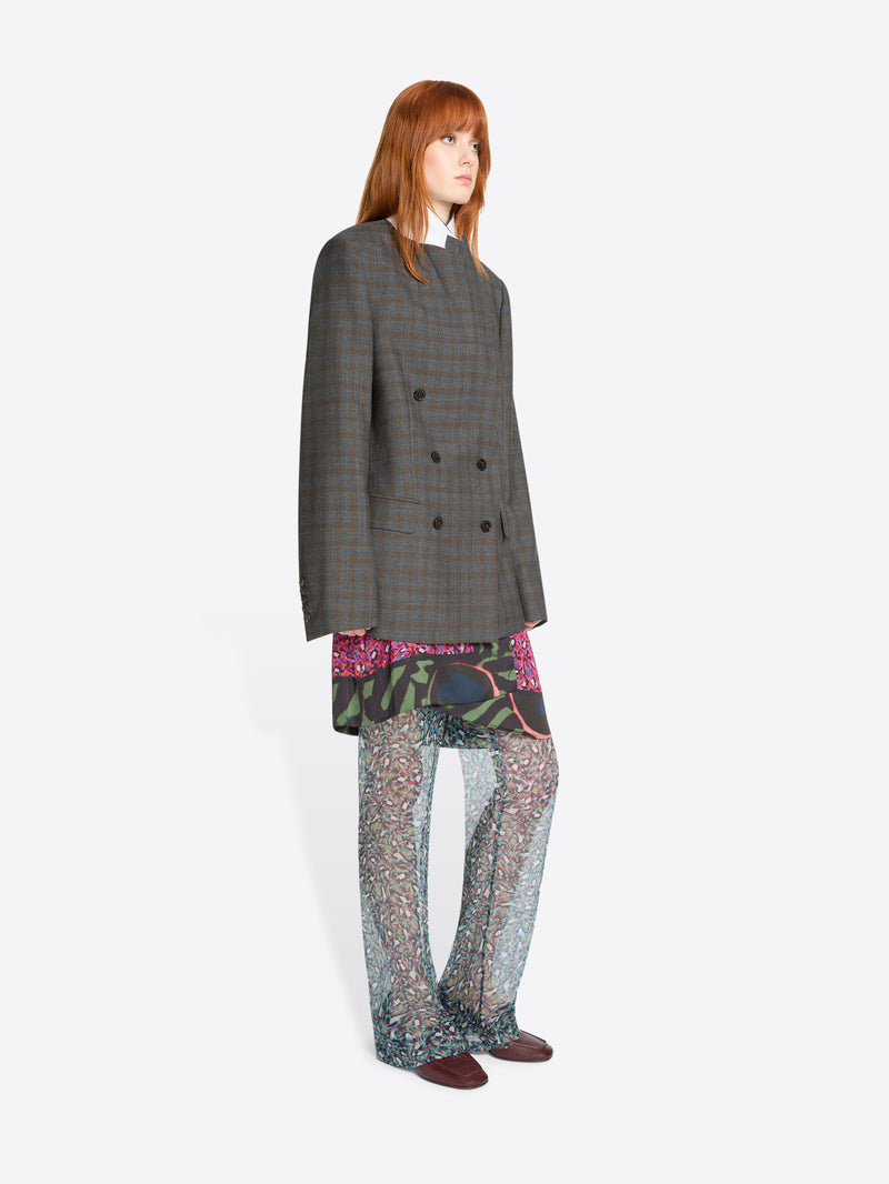 Woman wearing a gray checkered blazer with a colorful skirt and pants on a white background