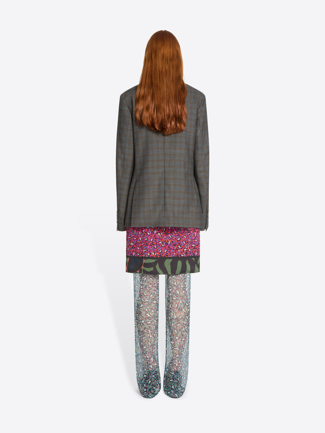 Back view of person wearing a gray blazer, patterned skirt, and pants on a white background